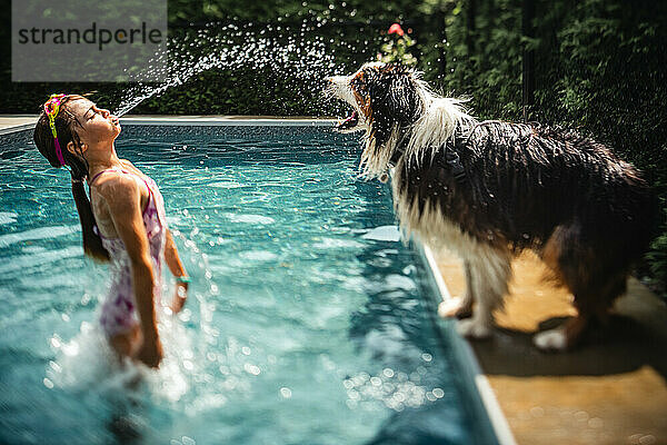 Mädchen planscht an einem heißen Sommertag mit ihrem Hund am Pool