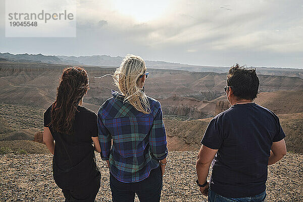 Drei Personen blicken von einem Aussichtspunkt auf den Grand Canyon  windig