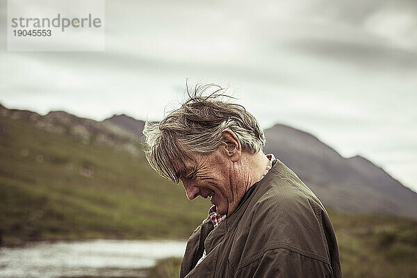 Rentner lacht und lächelt beim Angeln in einem abgelegenen Flussberg