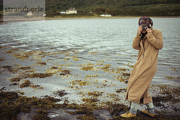 Mädchen macht Foto mit Einwegkamera am Bergsee