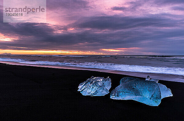 Sunset with blocks of ice in black sand beach  Iceland
