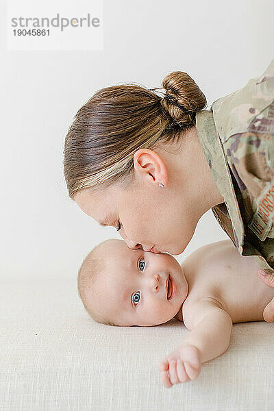 Mutter im aktiven Militärdienst küsst die Wange ihres Babys