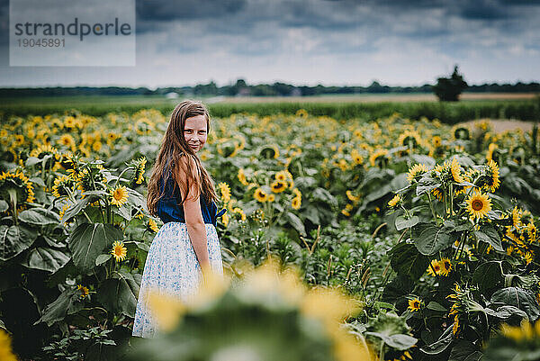 Porträt eines lächelnden Mädchens in einem Sonnenblumenfeld