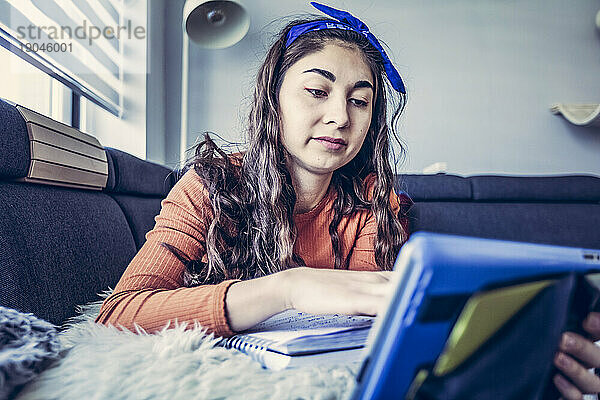 Weitwinkelaufnahme einer Studentin  die sich vom Tablet aus Notizen im Notizbuch macht