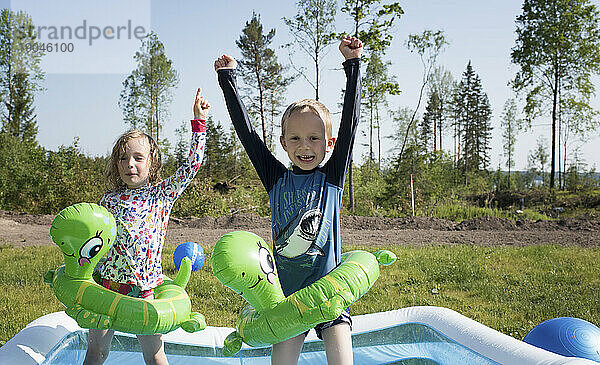 Zwei glückliche Kinder tanzen in einem Planschbecken