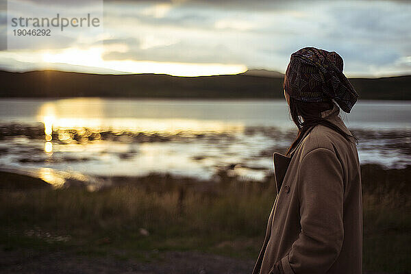 Eine Person beobachtet den Sonnenuntergang über einem abgelegenen Bergsee