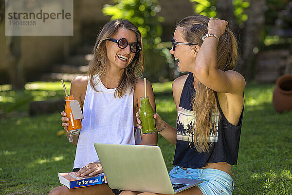 Zwei junge Frauen benutzen Laptop im Freien