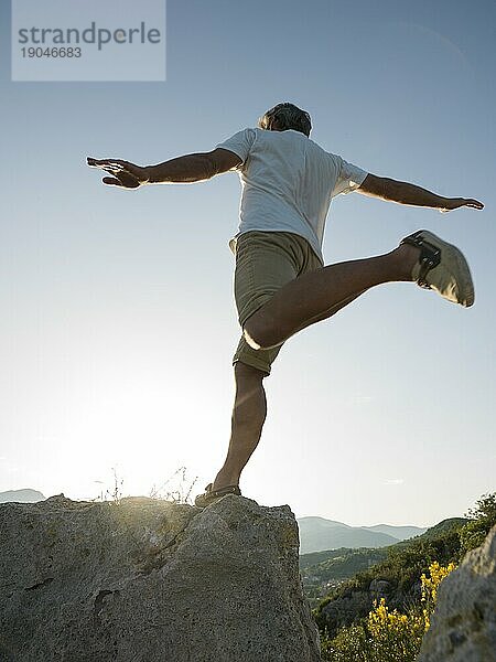 Mann springt auf Felsen über dem Meer