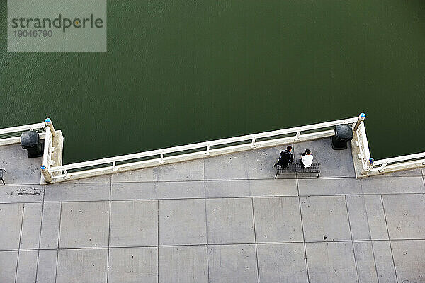 Blick aus der Vogelperspektive auf zwei Personen  die auf einer Bank neben einem Baseballpark in San Francisco  Kalifornien  sitzen.