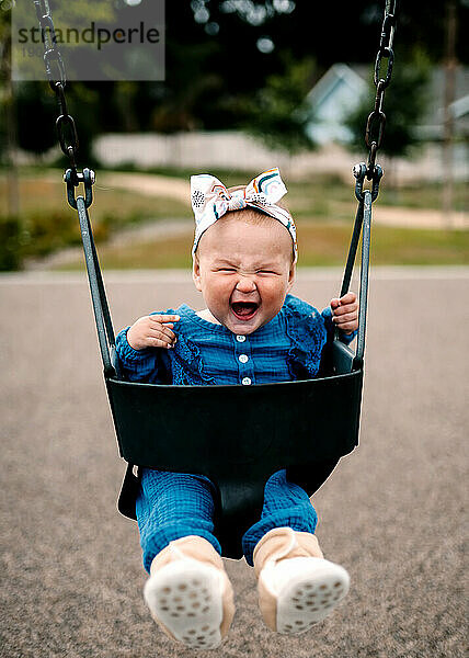 Baby lacht in der Schaukel im Park