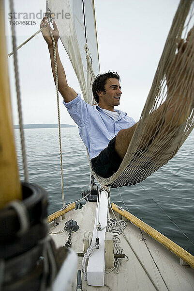 Mann entspannt sich in der Hängematte an Bord eines Segelboots  Casco Bay  Maine  Neuengland.