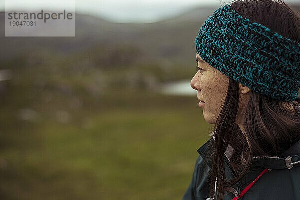 Mädchen mit Mütze blickt auf abgelegene Berge in Schottland
