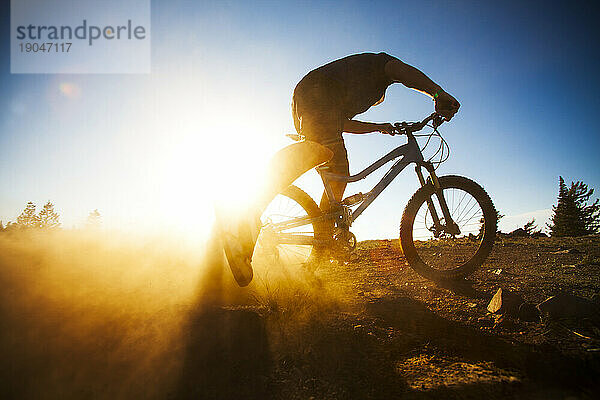 Ein Mann auf einem Mountainbike  die Silhouette der untergehenden Sonne.