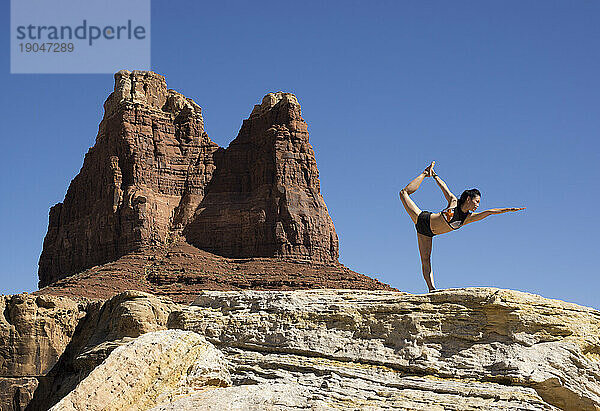 Frau macht eine Yoga-Pose im Freien in einer Wüstenumgebung.
