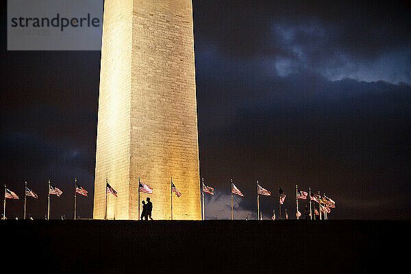 Zwei Menschen gehen am Washington Monument vorbei.