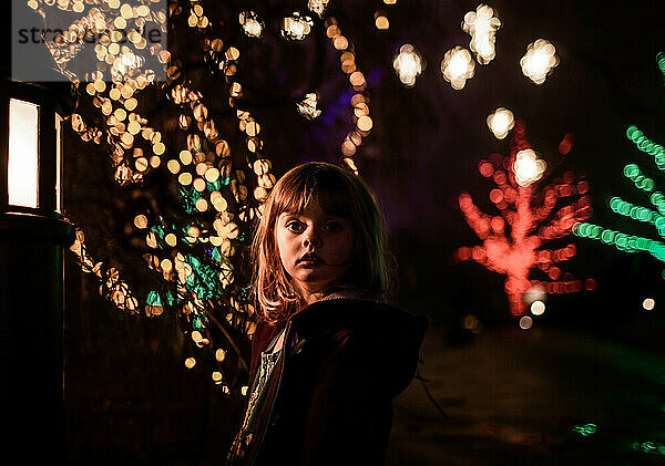 junges Mädchen in der Nacht mit Weihnachtsbeleuchtung und Bokeh