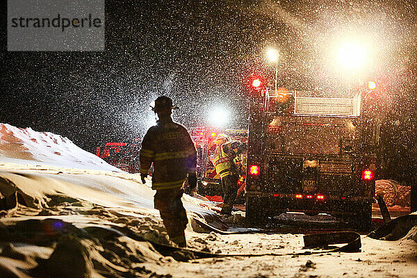 Feuerwehrleute bereiten sich auf die Brandbekämpfung in einem nächtlichen Schneesturm in Vermont vor.