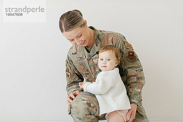 Baby kuschelt mit einer aktiven Militärmutter in Uniform