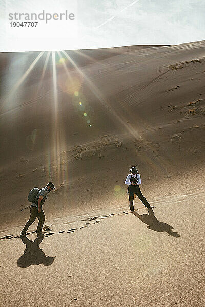 Frau überprüft ihr Telefon und wartet auf ihren männlichen Begleiter beim Wandern in den Dünen
