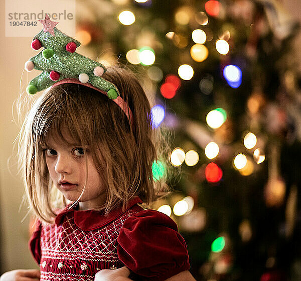 Junges Mädchen trägt rotes Kleid und Weihnachtsbaum-Stirnband