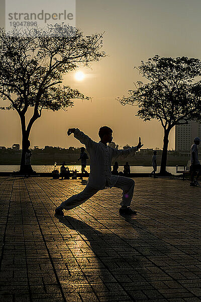 Silhouette eines jungen Erwachsenen  der bei Sonnenuntergang Tai Chi praktiziert  Phnom Penh  Kambodscha.