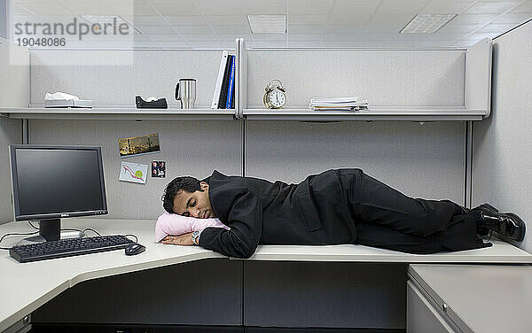 Ein Mann schläft bei der Arbeit auf seinem Schreibtisch.