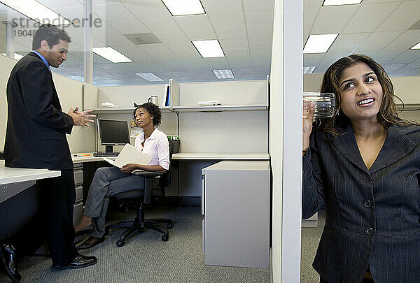 Eine Arbeiterin hört ihre Kollegen durch eine Kabinenwand ab.