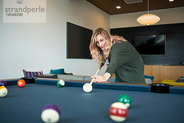 Junge Frau spielt Billard in der Wohnung