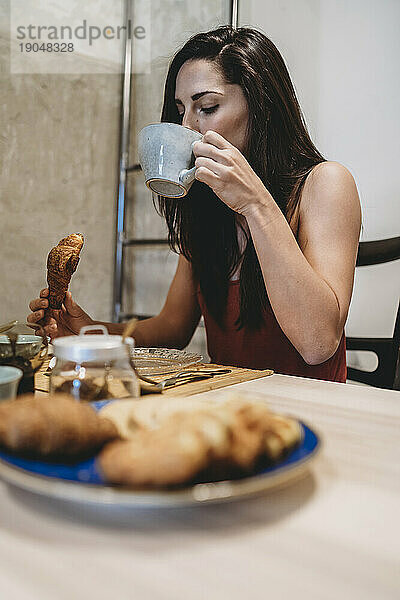 Junge Frau frühstückt morgens zu Hause