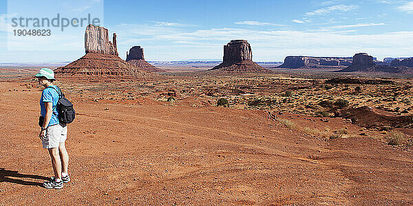 Eine Wanderin steht allein im Monument Valley und in den Sandsteinhügeln.