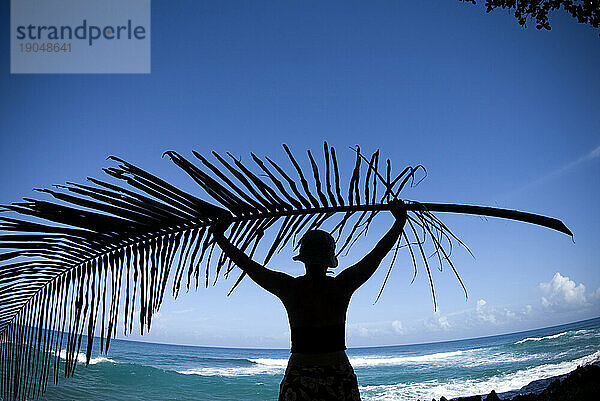 Frau hält einen Palmenzweig in Richtung Meer  Naturas Cabanas  Dominikanische Republik.