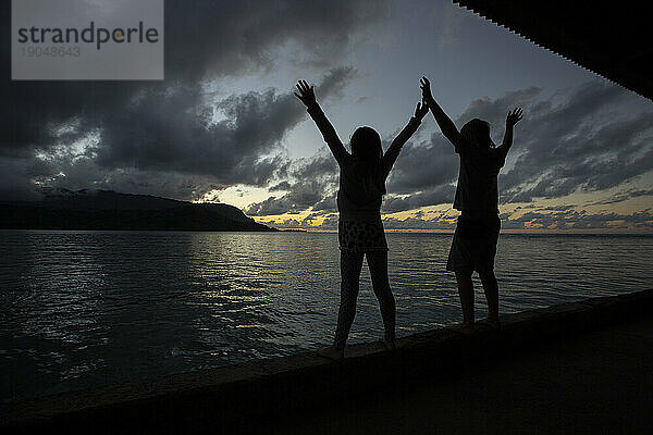 Silhouette von Kindern  die sich über den Sonnenuntergang freuen  Hanalei Bay  Kauai