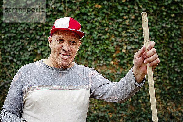 Porträt eines älteren Mannes mit Baseballkappe und breitem Grinsen bei der Gartenarbeit