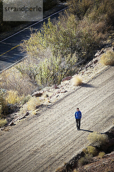 Erhöhte Ansicht einer einsamen Frau  die mitten auf einer unbefestigten Straße steht. Utah.