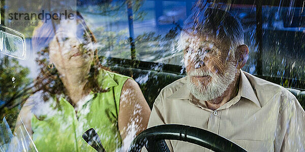 Eine Frau mittleren Alters und ein älterer Mann sitzen im Fahrerhaus eines Lastwagens