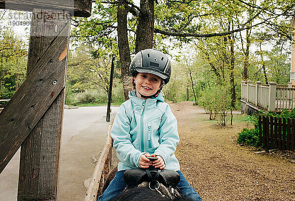Mädchen im Alter von 4 Jahren lächelt beim Reiten im Wald