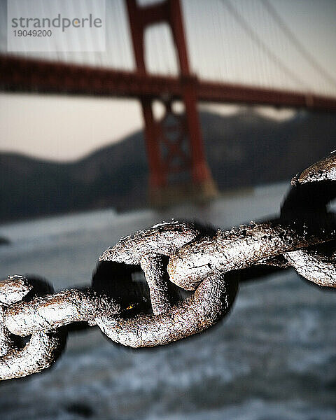 Nahaufnahme einer verrosteten Metallkette mit der Golden Gate Bridge im Hintergrund  San Francisco  Kalifornien.