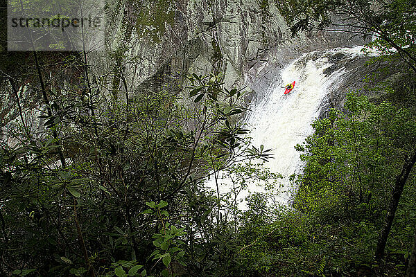 Mann fährt mit dem Kajak einen Wasserfall entlang (Aktion)