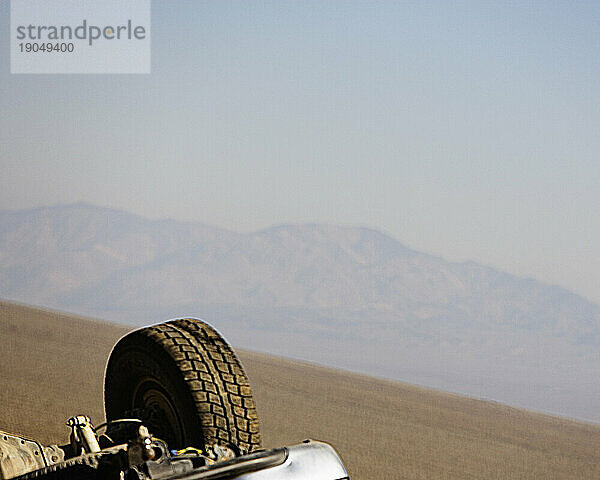 Das Hinterrad eines umgedrehten Autos in der Wüste. Foto manipuliert.