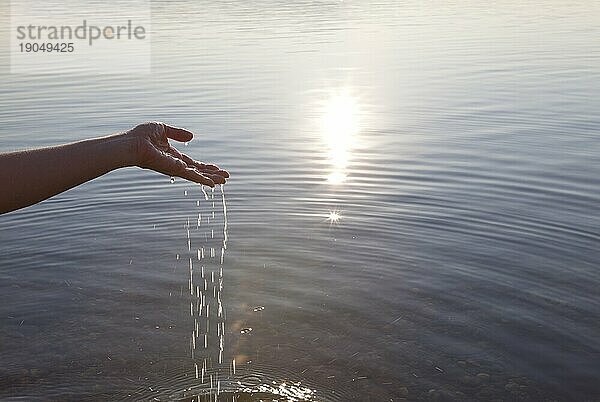 Wasser ergießt sich aus Händen in einen ruhigen See