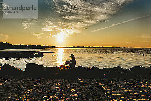 Reife Frau sitzt friedlich am Strand von Cape Cod in der goldenen Stunde