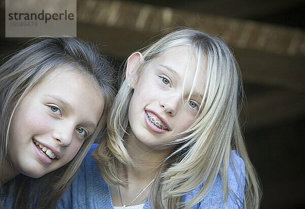 Zwei junge Mädchen lächeln in die Kamera.