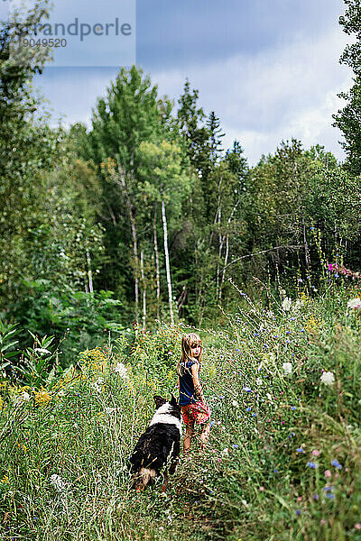 Junges Mädchen  das mit seinem australischen Schäferhund durch einen Wald geht