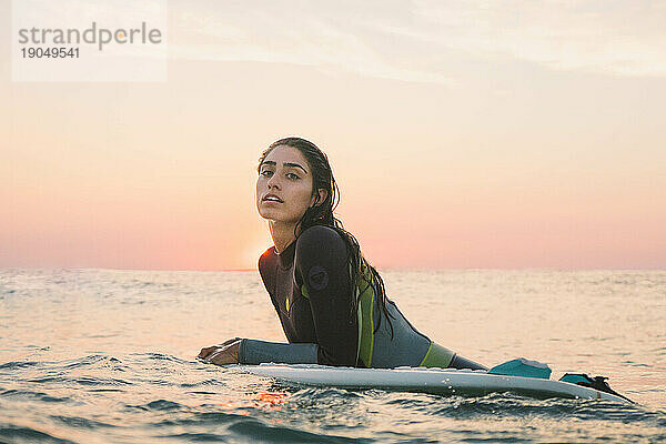 Surfermädchen posiert im Wassersonnenuntergang