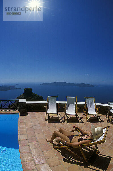 Frau entspannt sich am Pool und blickt auf die Caldera von Santorini  Griechenland.