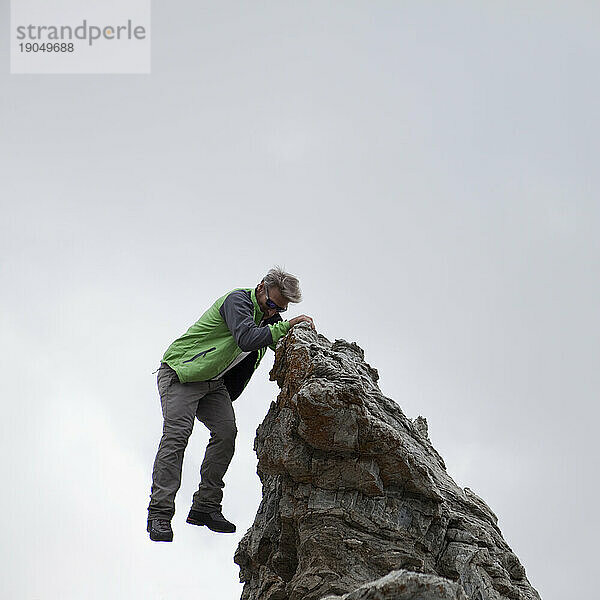 Wanderer springt von Gipfelfelsen
