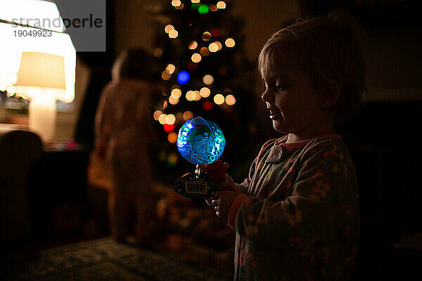 Kleinkind/Baby hält Spielzeug und lächelt am Weihnachtsmorgen