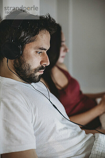 Junges Paar im Bett und schaut auf sein Smartphone