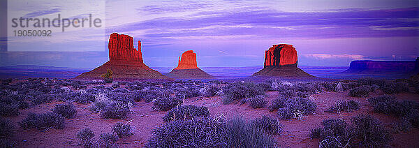 Abenddämmerung im Monument Valley an der Grenze zwischen Utah und Arizona mit den drei bekanntesten Hügeln in der Ferne; East und West Mitten Buttes und Merrick Butte.