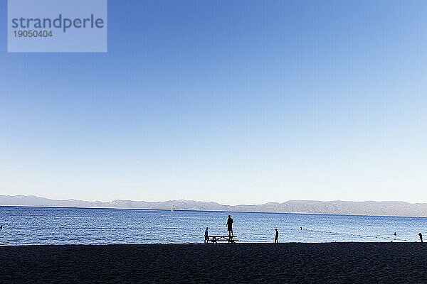 Silhouetten von Menschen im Gegenlicht am Strand von Lake Tahoe.